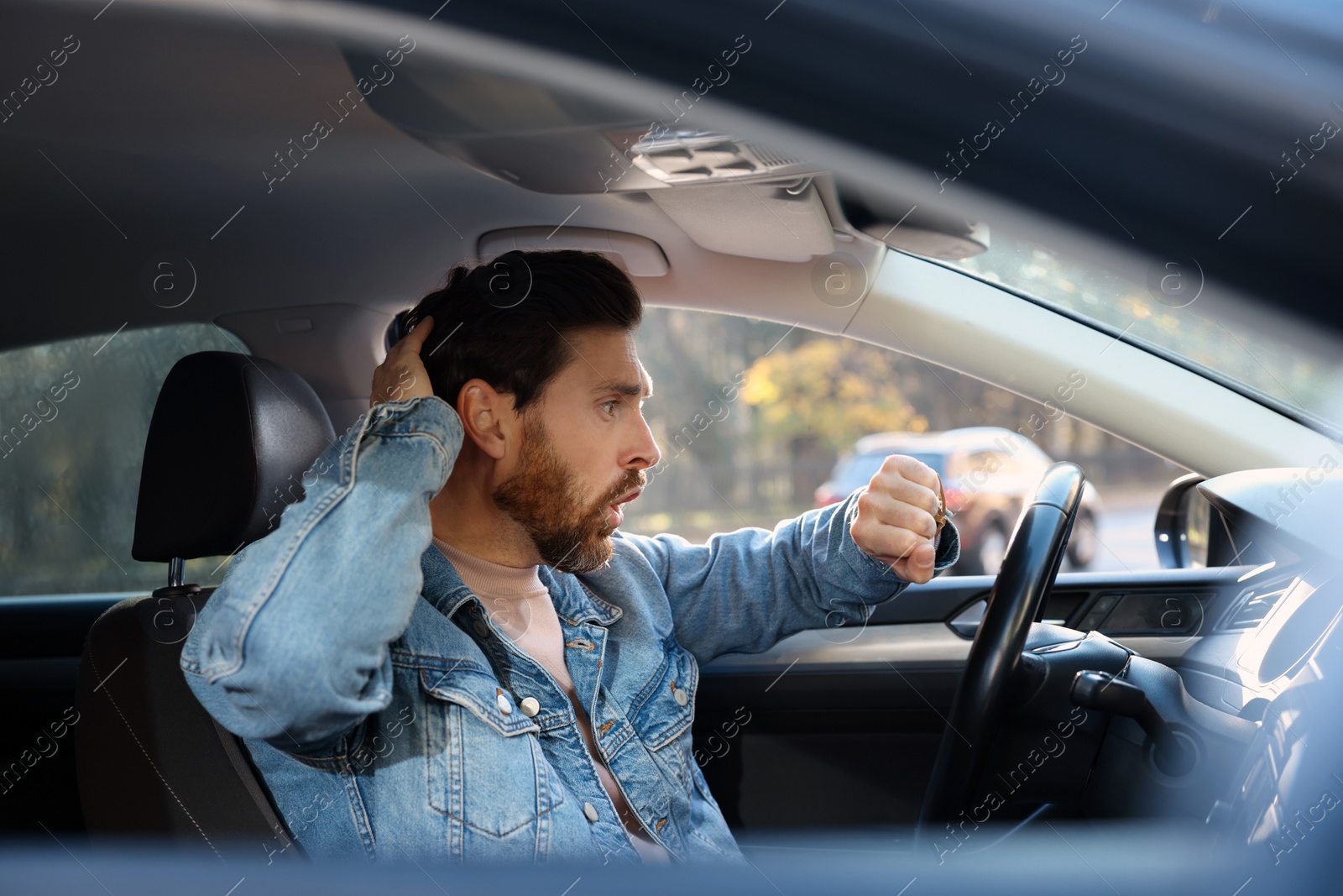 Photo of Emotional man checking time on watch in car. Being late concept