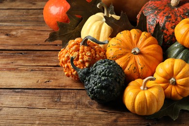 Thanksgiving day. Many different pumpkins and dry leaves on wooden table, space for text