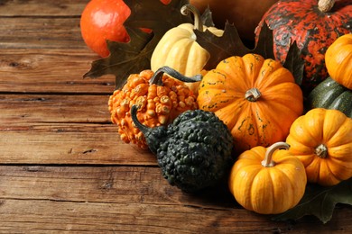 Photo of Thanksgiving day. Many different pumpkins and dry leaves on wooden table, space for text