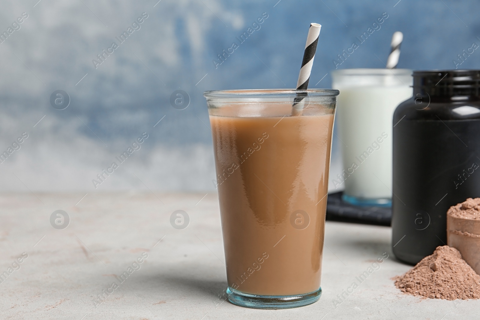 Photo of Glass of chocolate protein shake and powder on table. Space for text