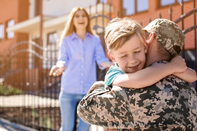 Photo of Male soldier hugging with his son outdoors. Military service