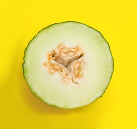 Photo of Half of ripe tasty melon on yellow background, top view