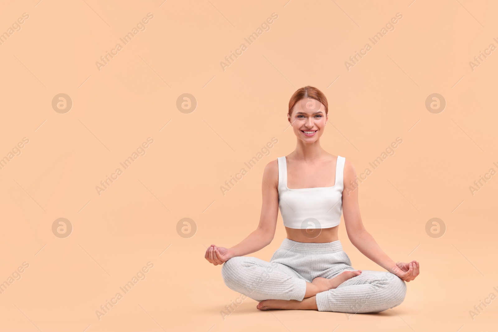 Photo of Beautiful young woman practicing yoga on beige background, space for text. Lotus pose