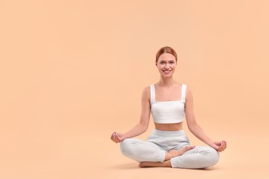 Photo of Beautiful young woman practicing yoga on beige background, space for text. Lotus pose