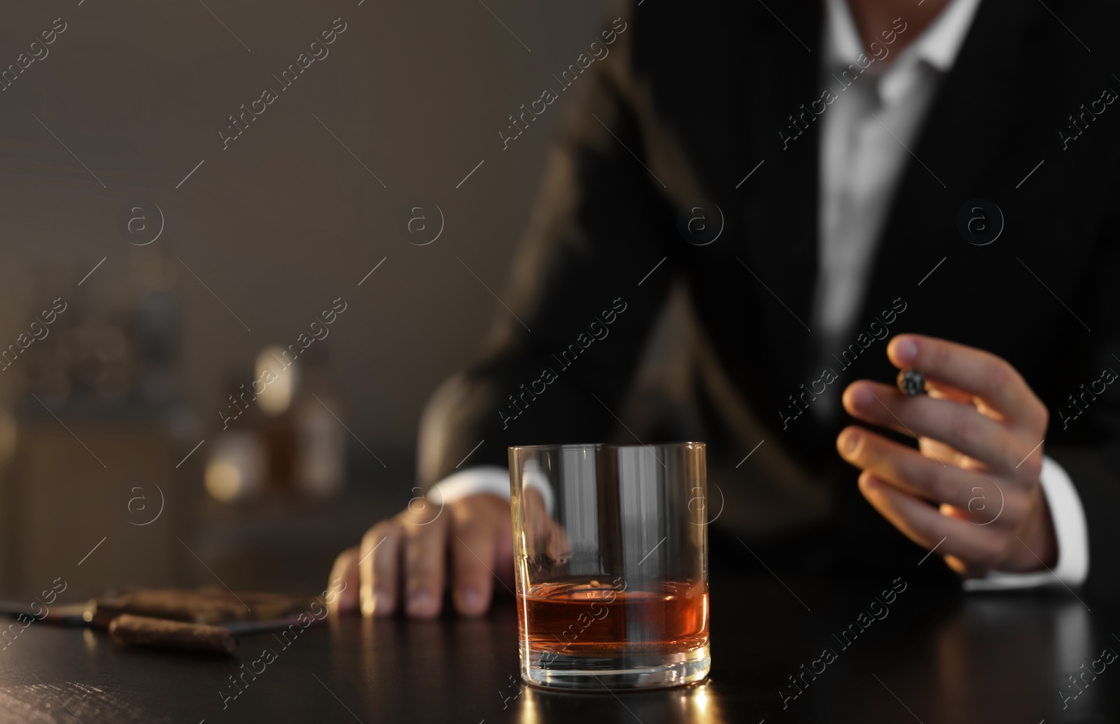 Photo of Man with glass of whiskey and cigar sitting at table, closeup. Space for text