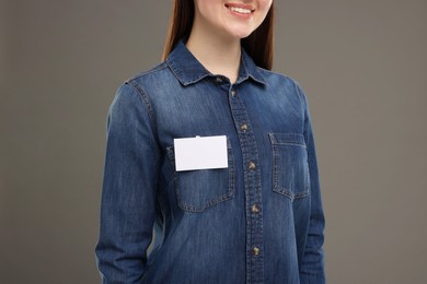 Woman with blank badge on grey background, closeup