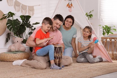 Photo of Happy family playing together near toy wigwam at home