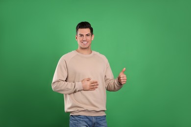 Photo of Happy healthy man touching his belly on green background
