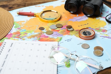 Photo of Different travel accessories and world map on table, closeup. Planning summer vacation trip