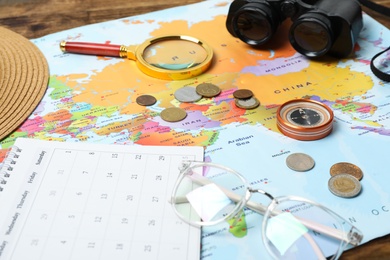 Different travel accessories and world map on table, closeup. Planning summer vacation trip