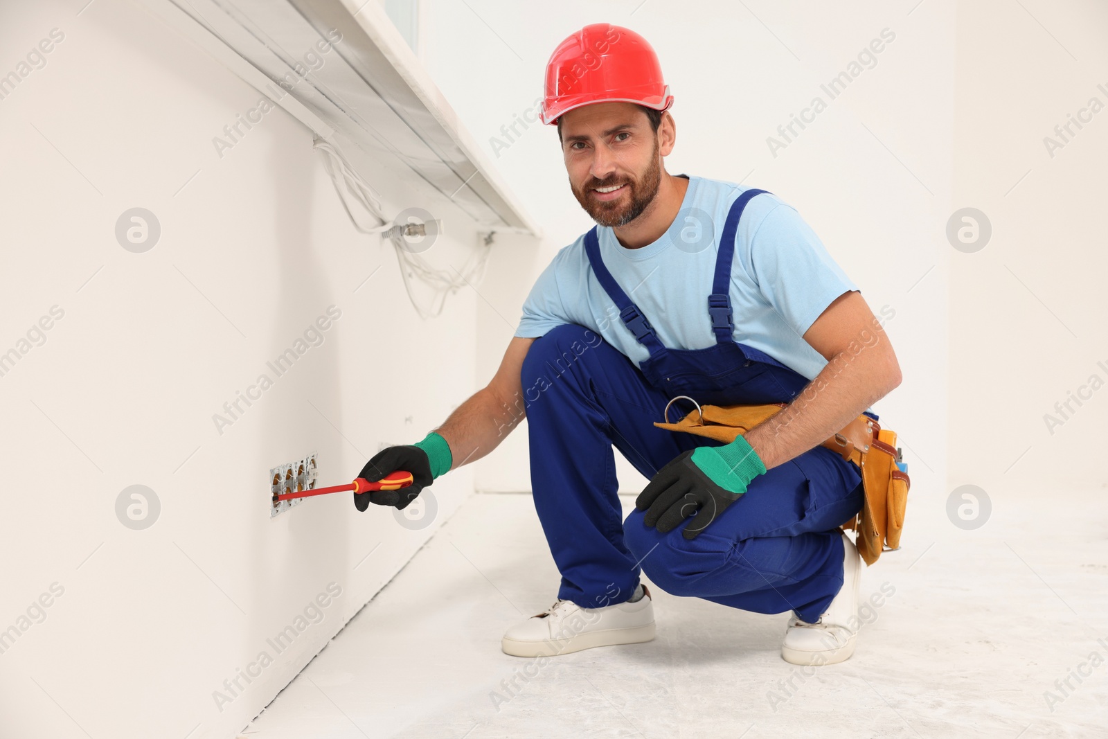 Photo of Electrician with screwdriver repairing power sockets indoors