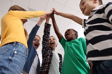 Photo of Happy children giving high five at school, low angle view