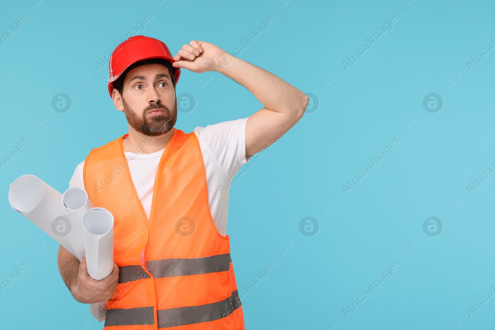 Photo of Confused architect in hard hat with drafts on light blue background, space for text