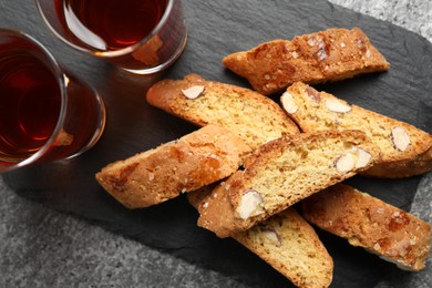 Photo of Tasty cantucci and glasses of liqueur on grey table, top view. Traditional Italian almond biscuits