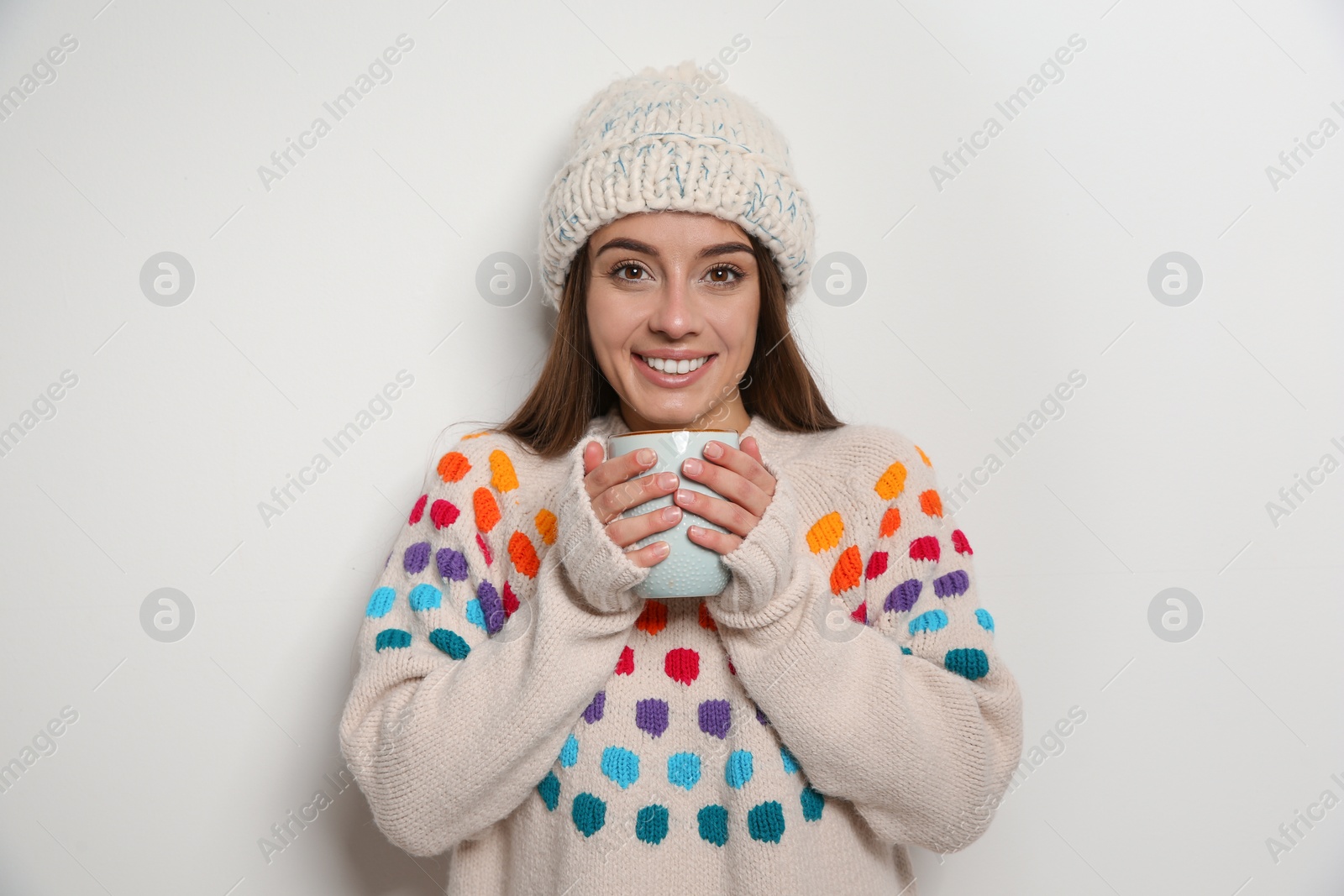 Photo of Beautiful young woman in warm sweater with cup of hot drink on white background