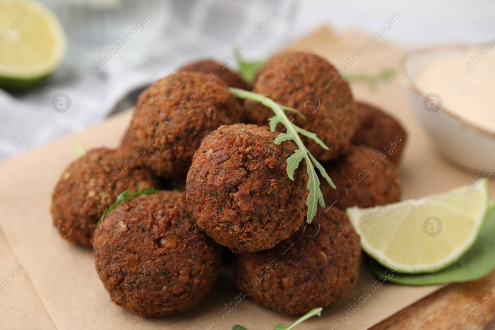 Photo of Delicious falafel balls, arugula and lime on table, closeup