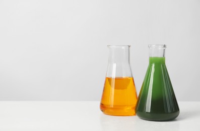 Photo of Glass flasks with different types of oil on white table, space for text