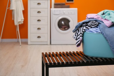 Photo of Laundry basket filled with clothes on bench in bathroom. Space for text