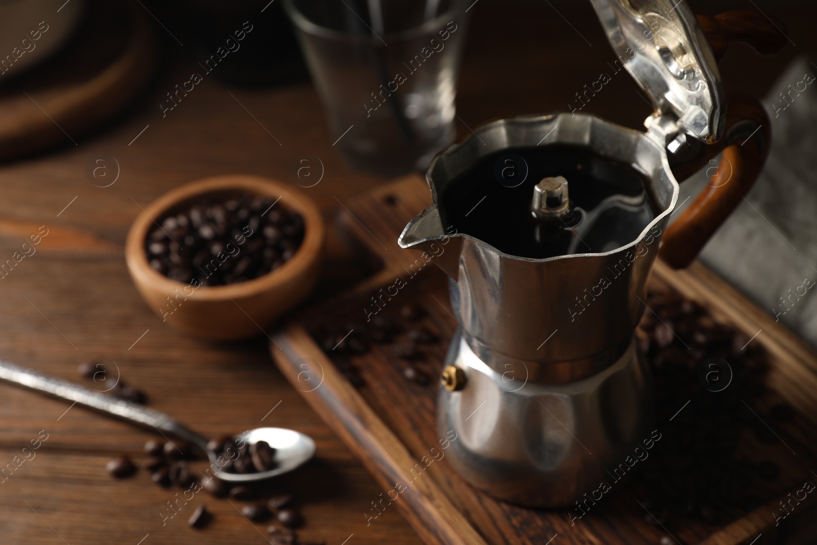 Photo of Brewed coffee in moka pot and beans on wooden table