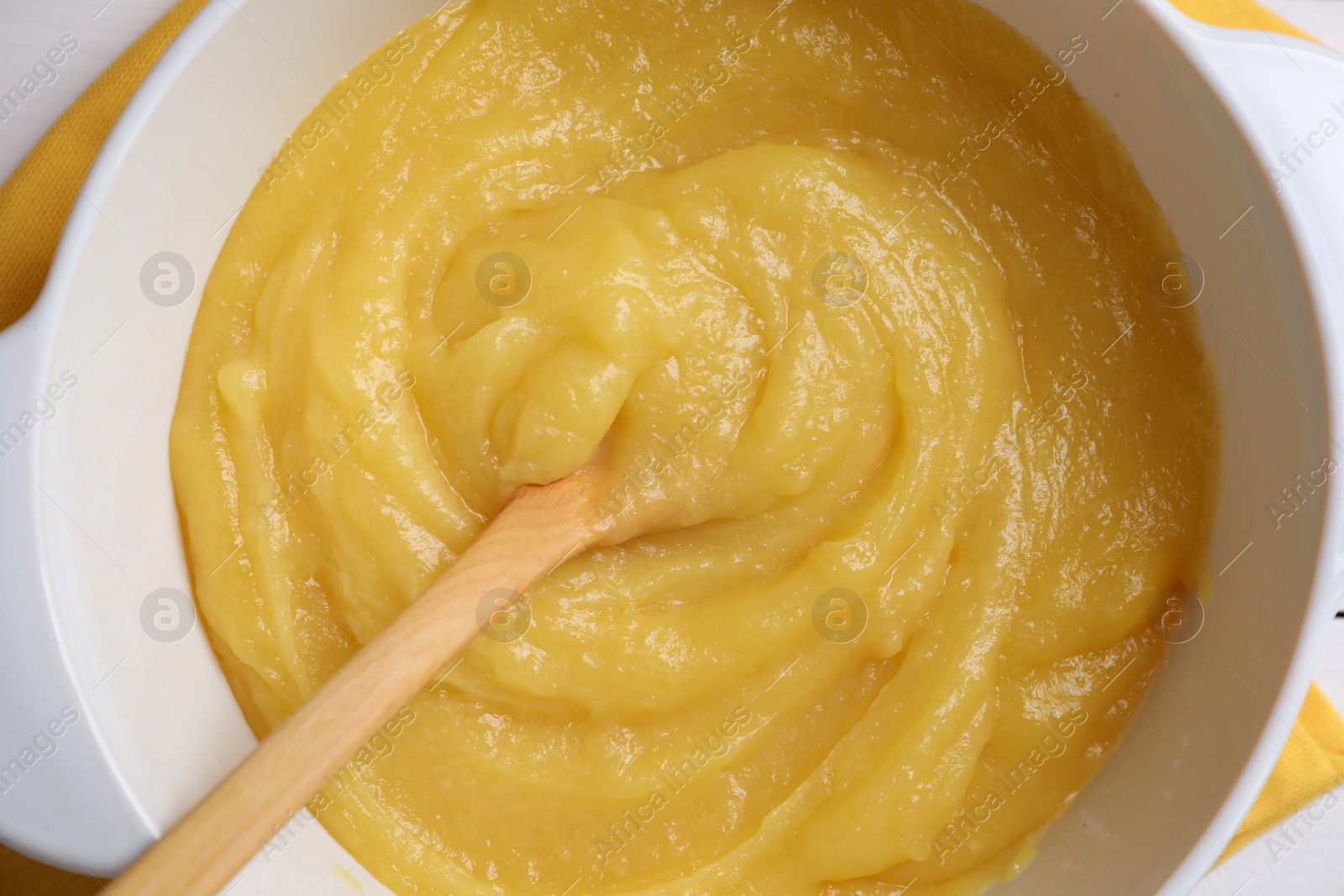 Photo of Delicious lemon curd in bowl and on table, top view