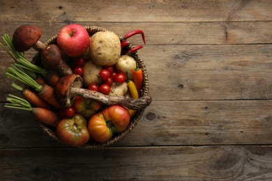 Photo of Basket with different fresh ripe vegetables and fruits on wooden table, top view. Space for text