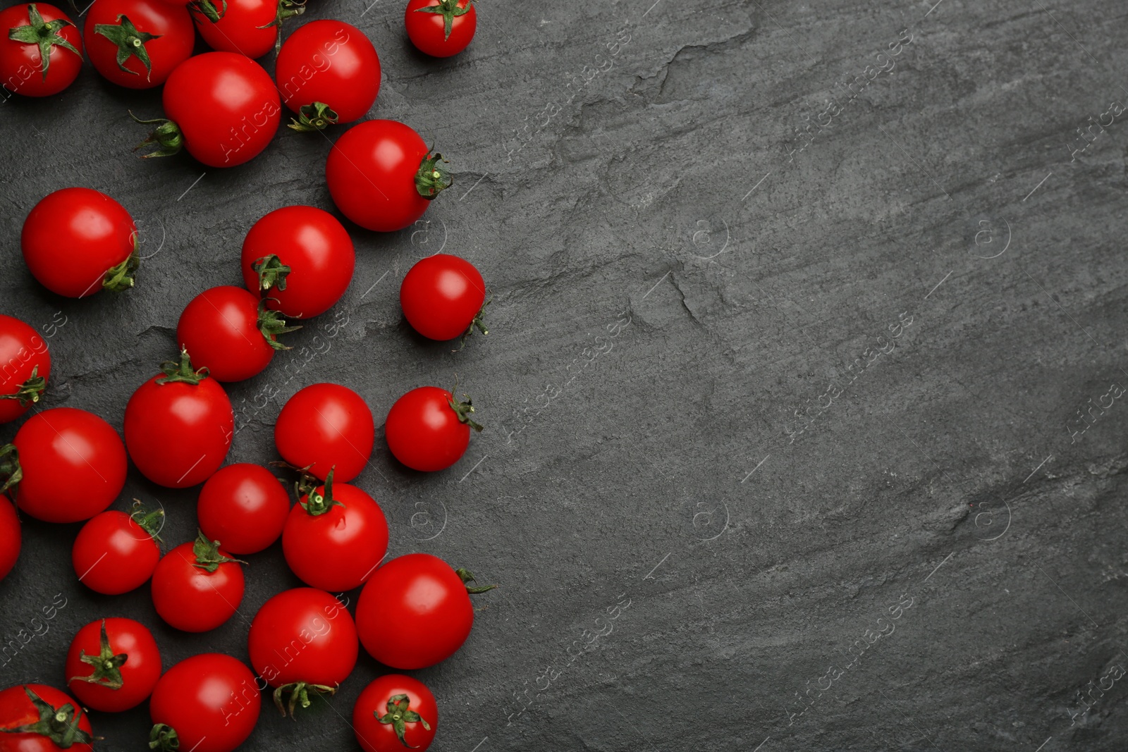 Photo of Fresh ripe cherry tomatoes on black table, flat lay. Space for text