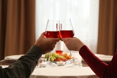 Photo of Couple clinking glasses of red wine on romantic dinner at home, closeup