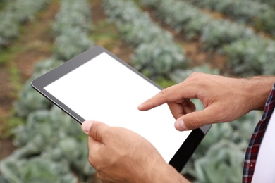 Photo of Man using tablet with blank screen in field, closeup. Agriculture technology