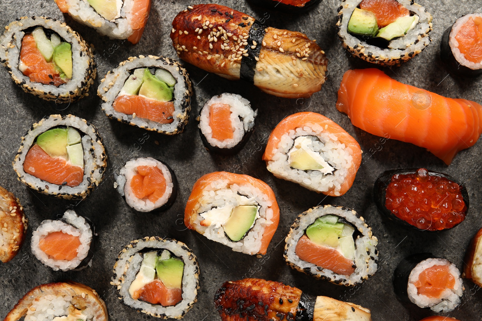 Photo of Different tasty sushi rolls on grey table, flat lay