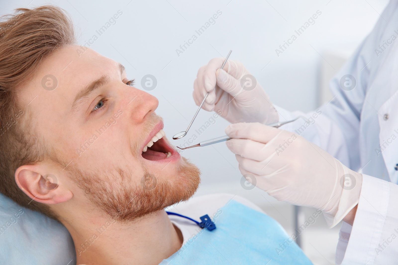 Photo of Dentist examining patient's teeth in modern clinic