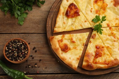 Photo of Delicious khachapuri with cheese on wooden table, flat lay