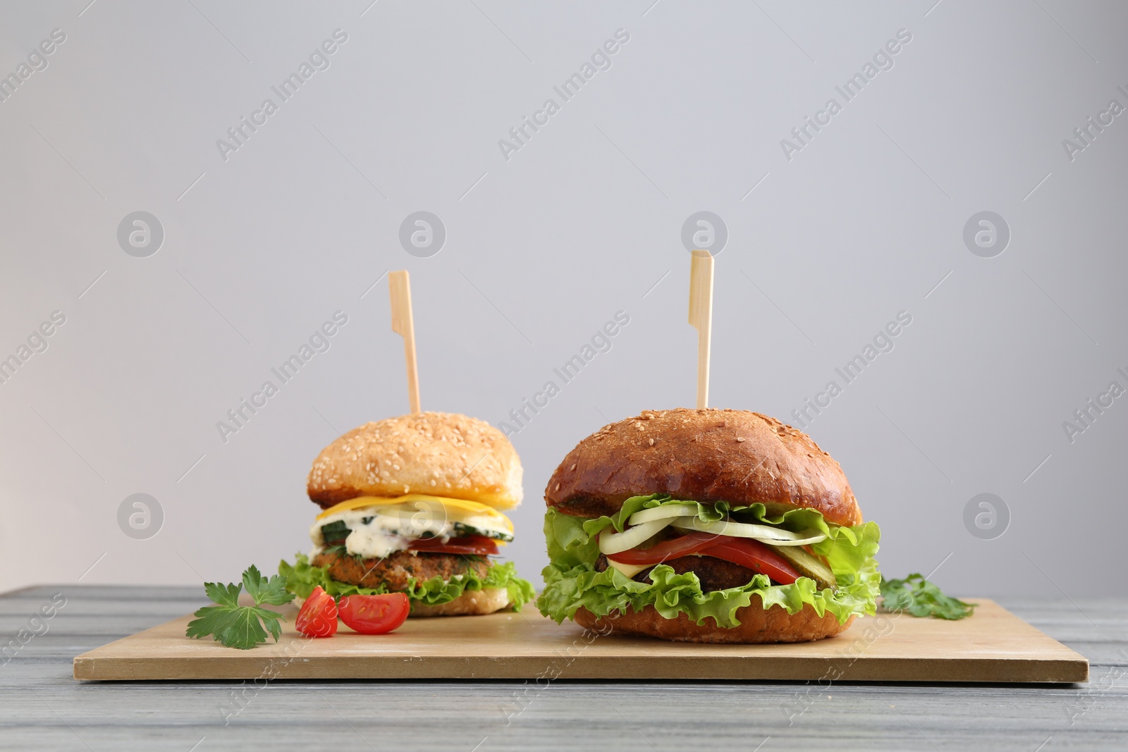 Photo of Delicious vegetarian burgers served on grey wooden table