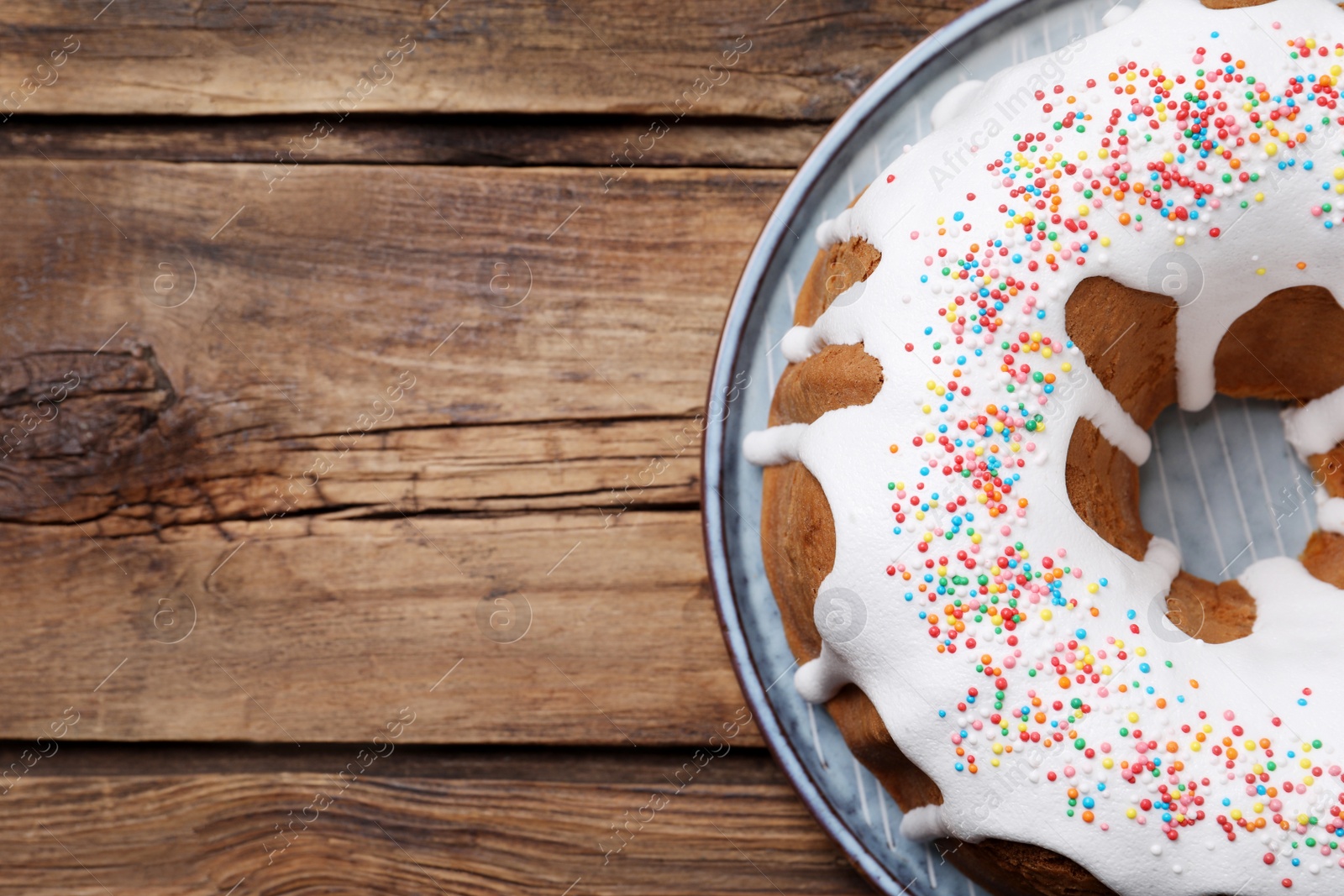 Photo of Glazed Easter cake with sprinkles on wooden table, top view. Space for text