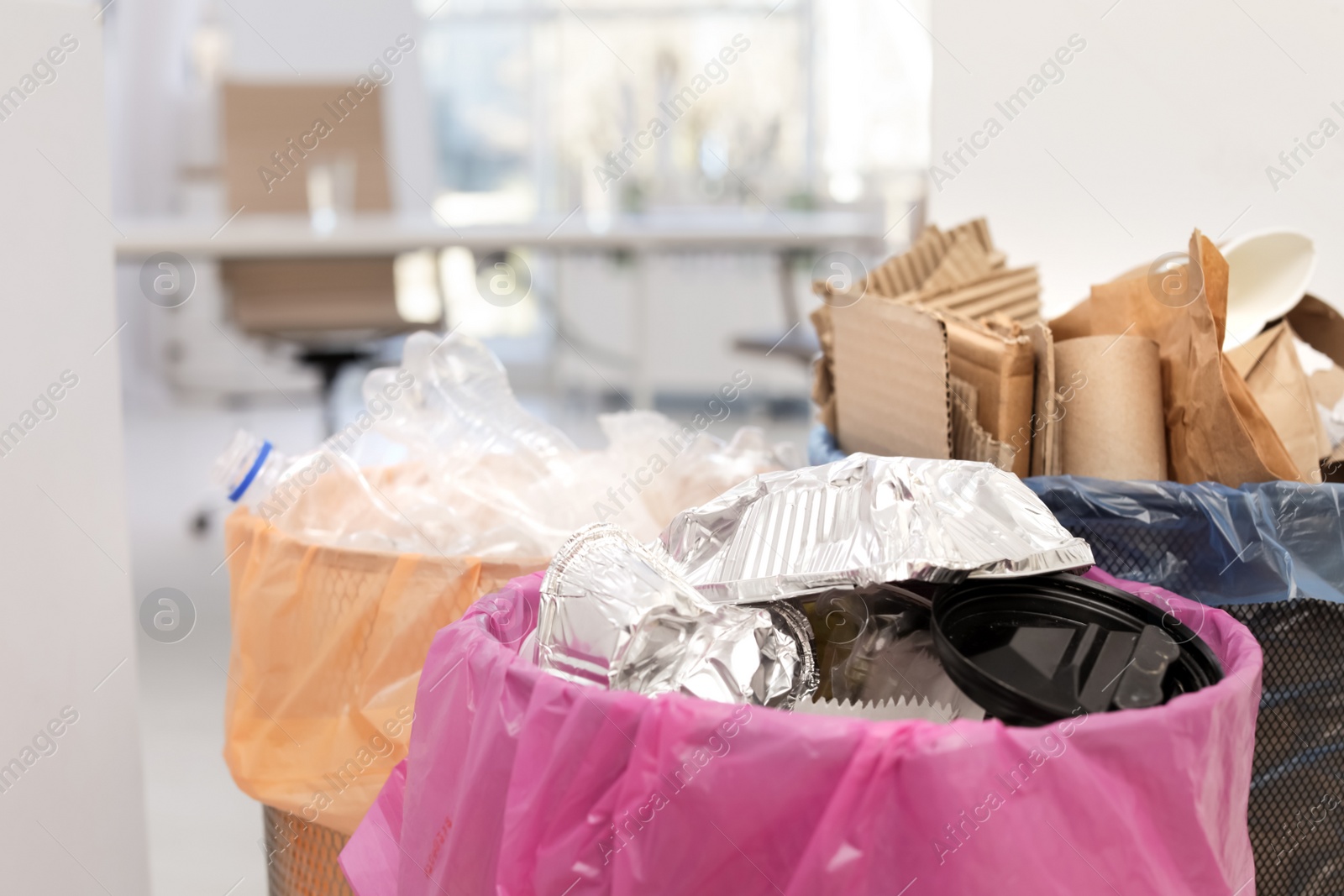 Photo of Full trash cans in modern office, closeup. Waste recycling