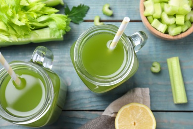 Photo of Celery juice and fresh ingredients on blue wooden table, flat lay