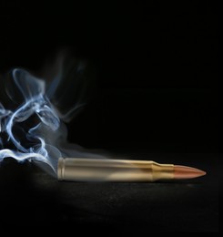 Image of One bullet with smoke on black background