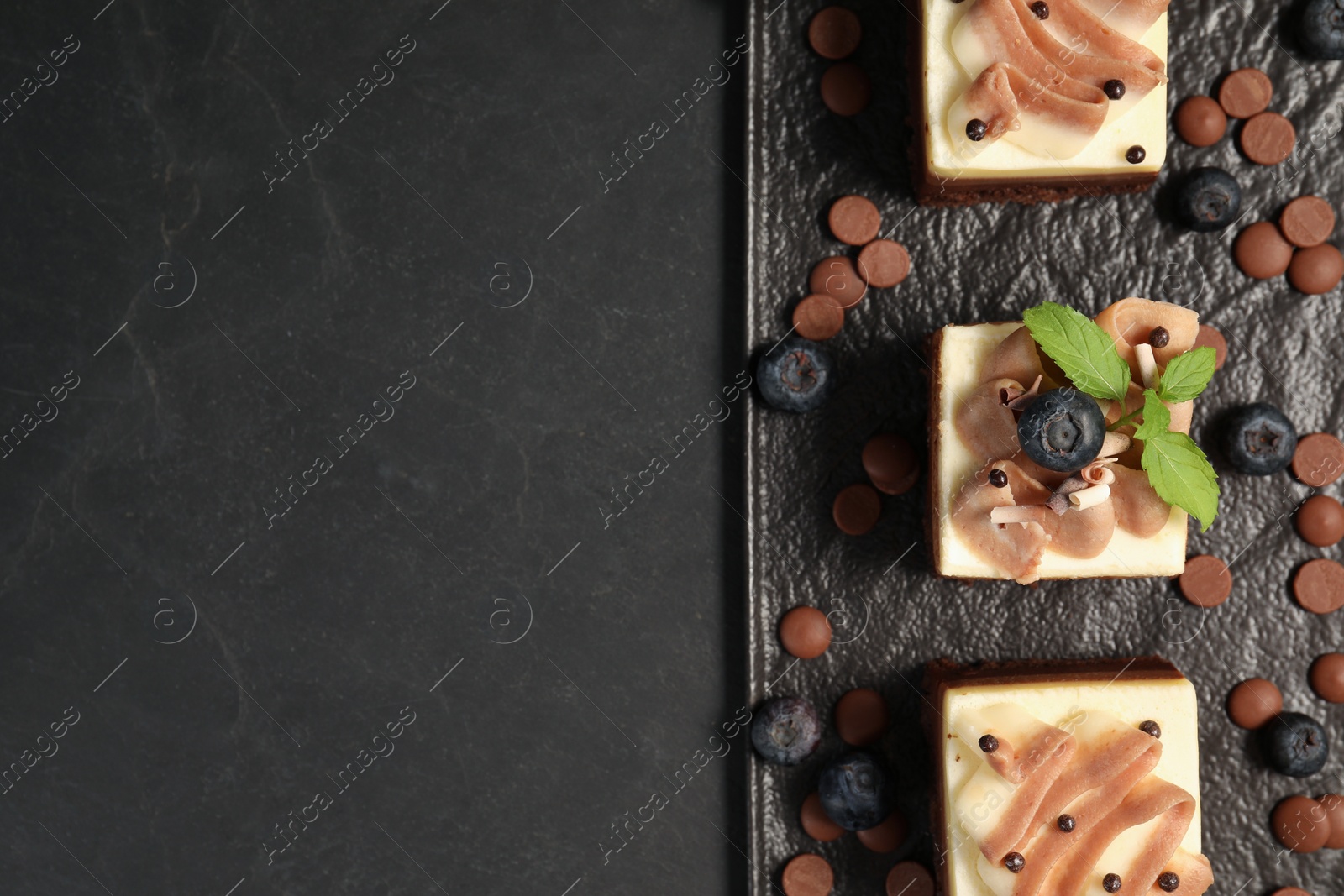 Photo of Pieces of triple chocolate mousse cake on black table, top view with space for text