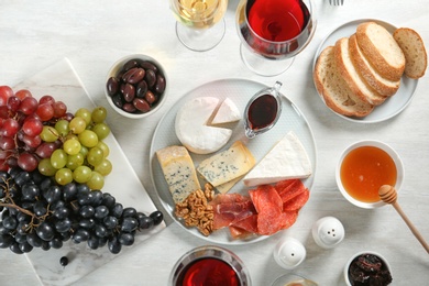 Photo of Wine and snacks served for dinner on light table, flat lay