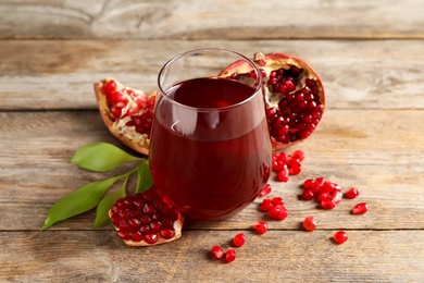 Photo of Glass of pomegranate juice and fresh fruits on wooden background