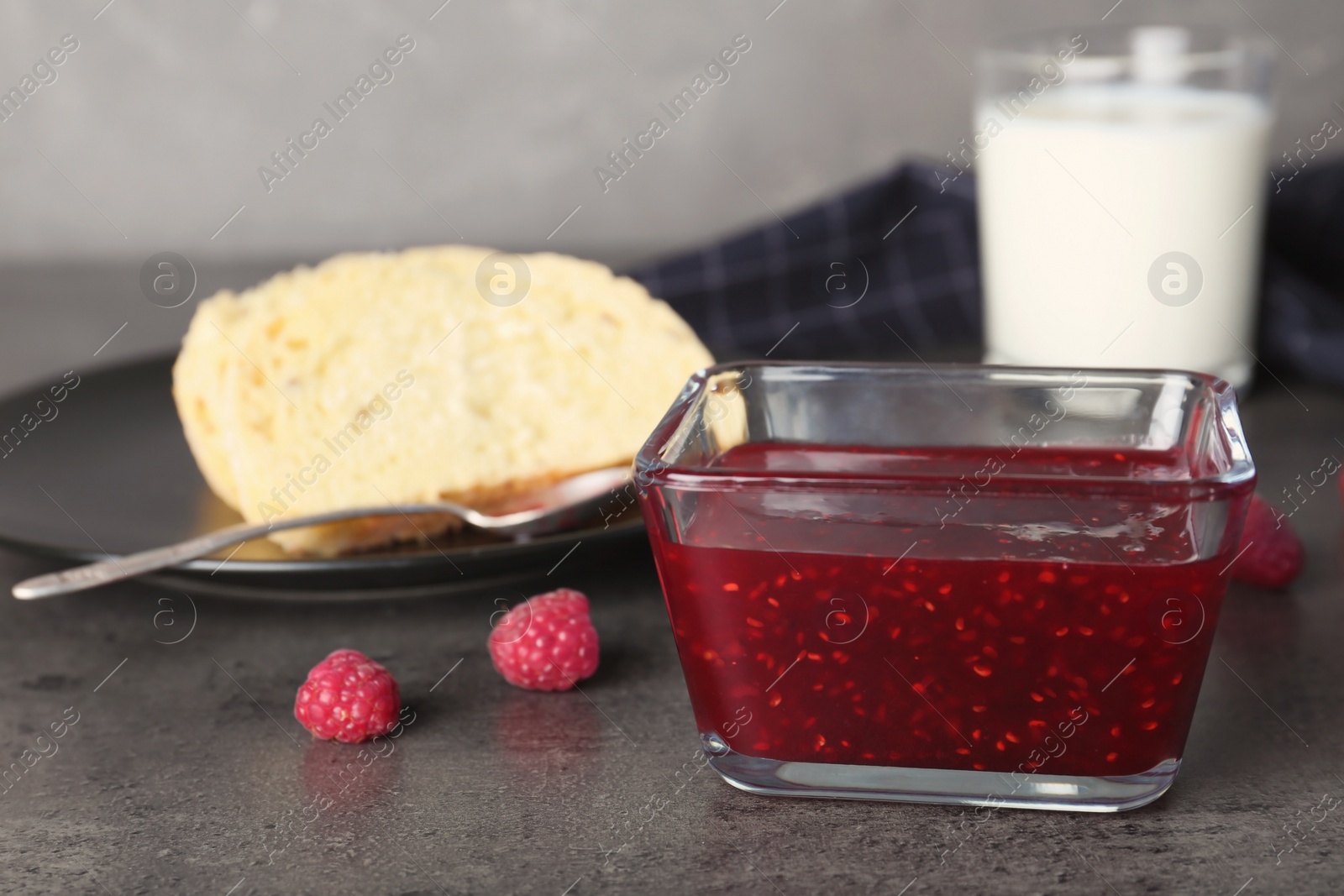 Photo of Bowl with delicious raspberry jam on table, closeup