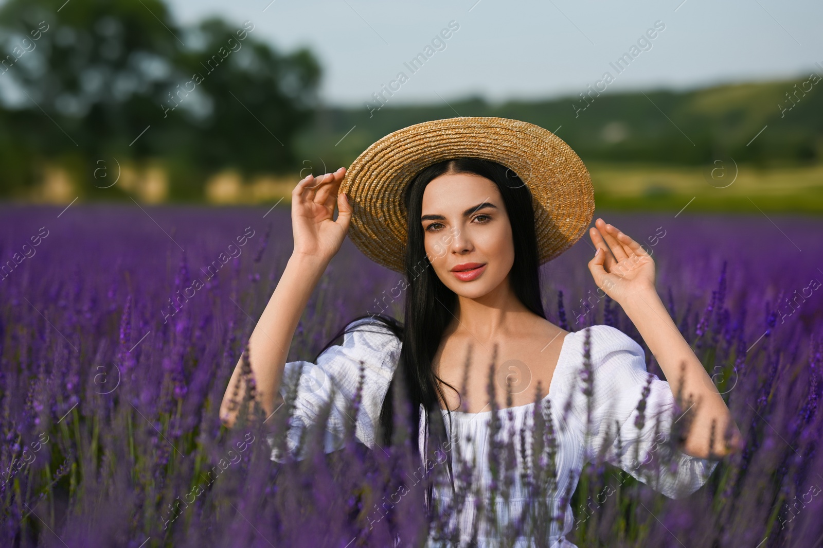 Photo of Beautiful young woman with straw hat in lavender field