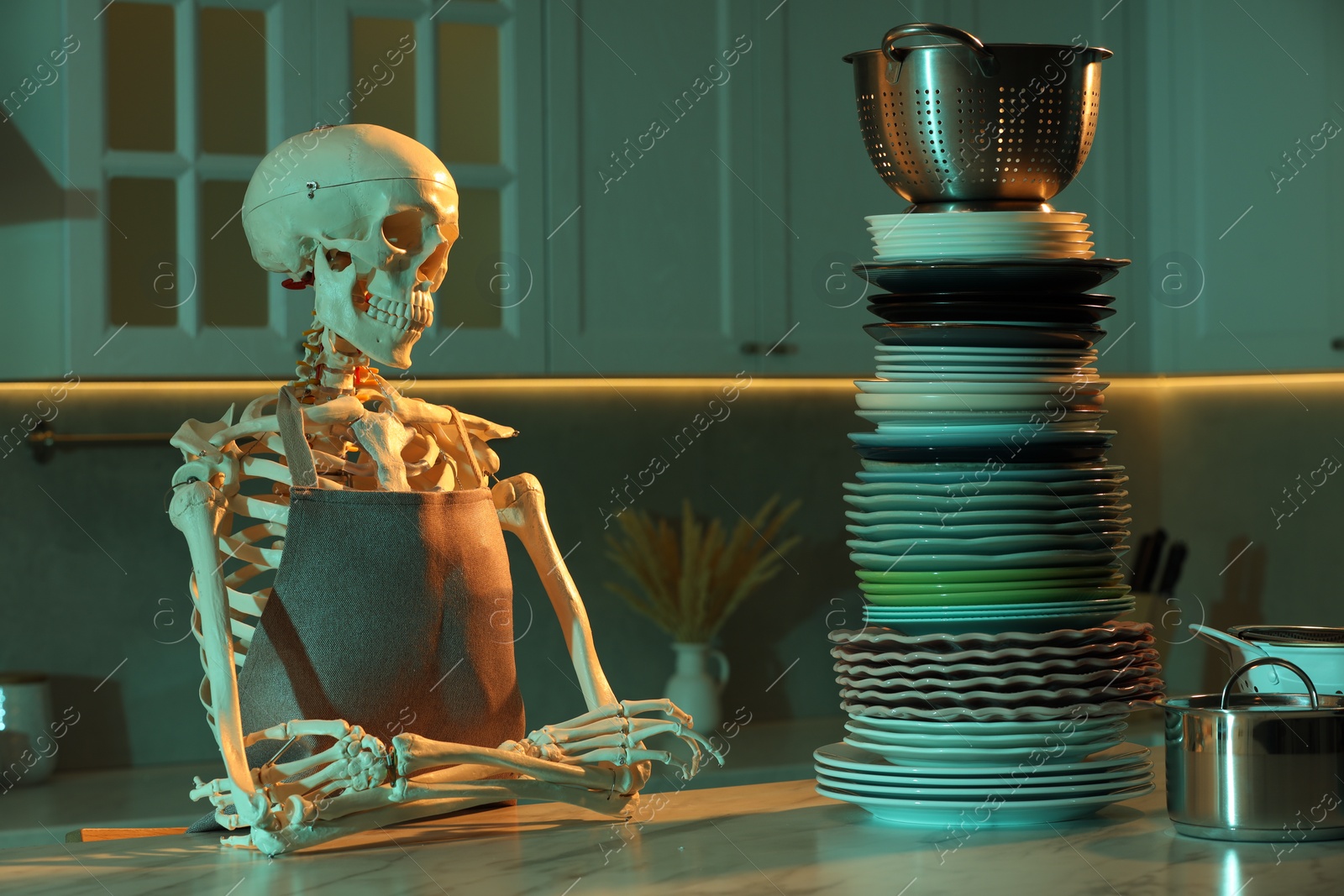 Photo of Human skeleton sitting at white marble table with clean dishware in kitchen at night