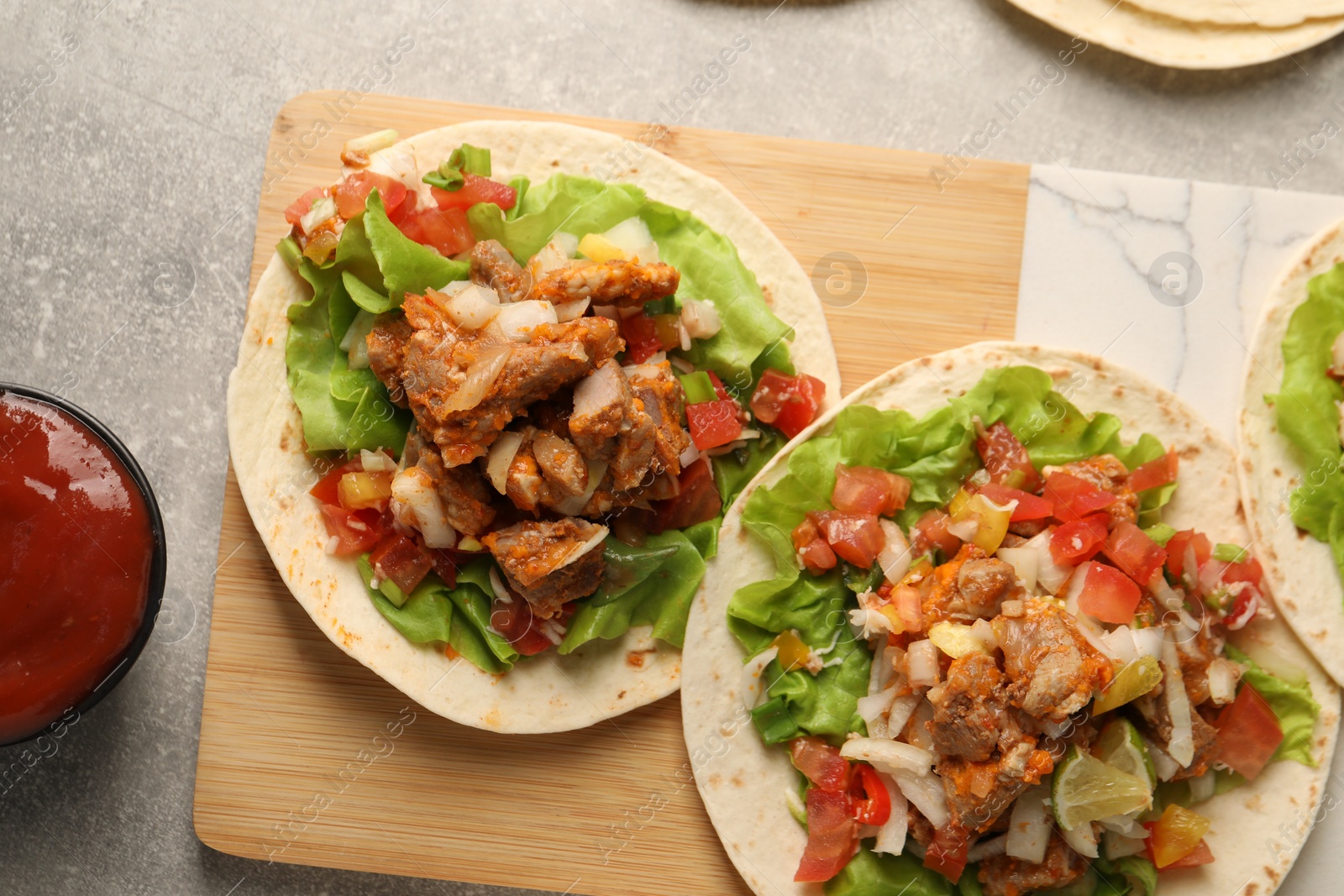 Photo of Delicious tacos with vegetables and meat on grey textured table, flat lay