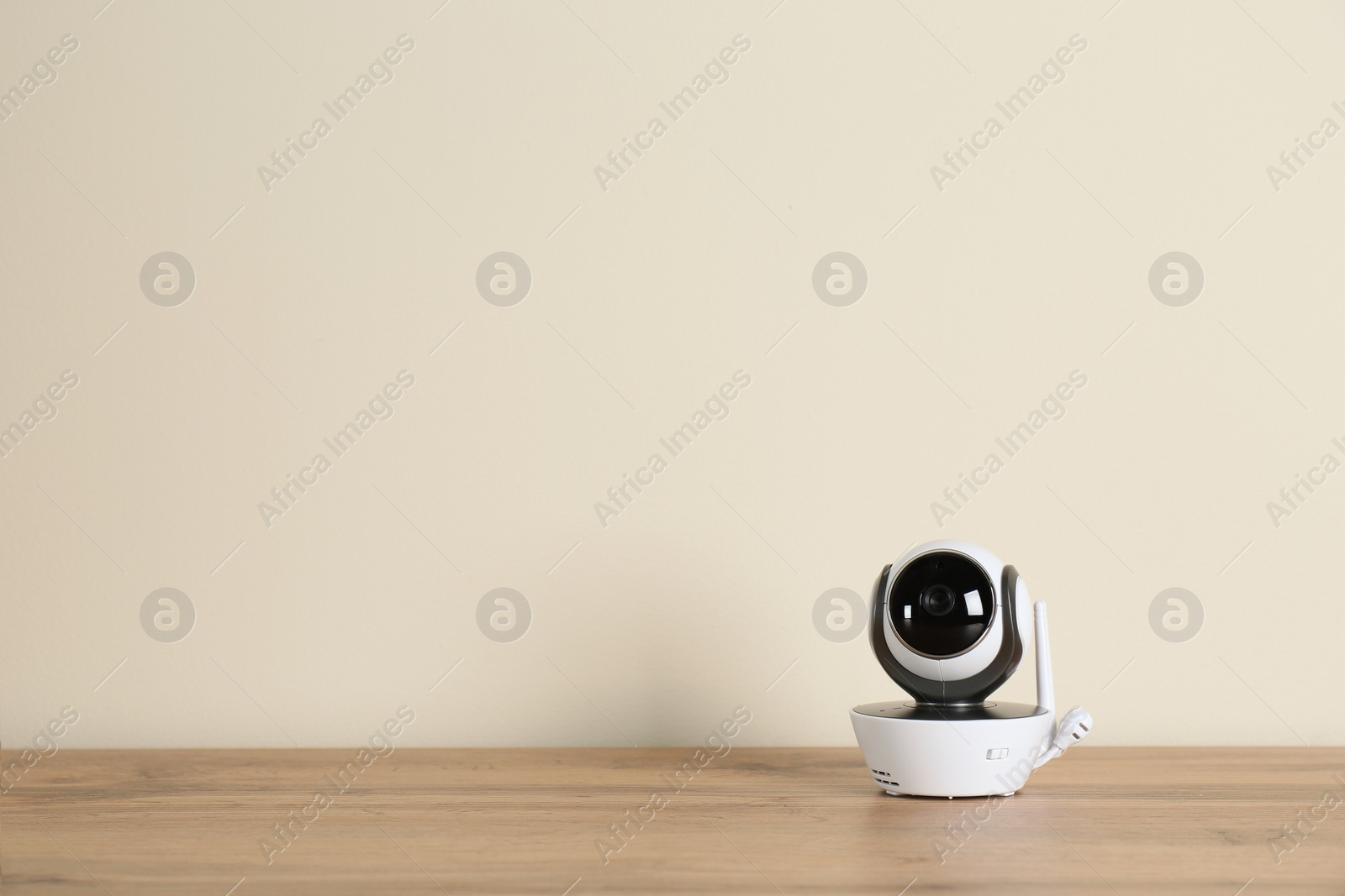 Photo of Baby monitor on wooden table, space for text. CCTV equipment