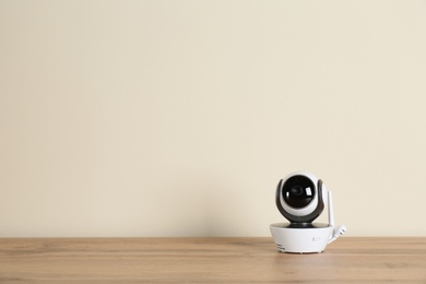Photo of Baby monitor on wooden table, space for text. CCTV equipment