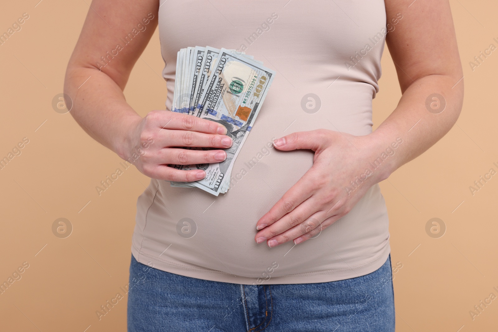 Photo of Surrogate mother. Pregnant woman with dollar banknotes on beige background, closeup