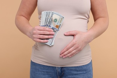 Surrogate mother. Pregnant woman with dollar banknotes on beige background, closeup