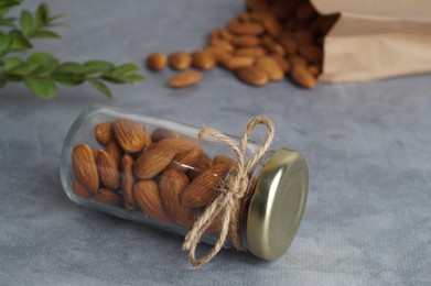 Jar with delicious almonds on grey table