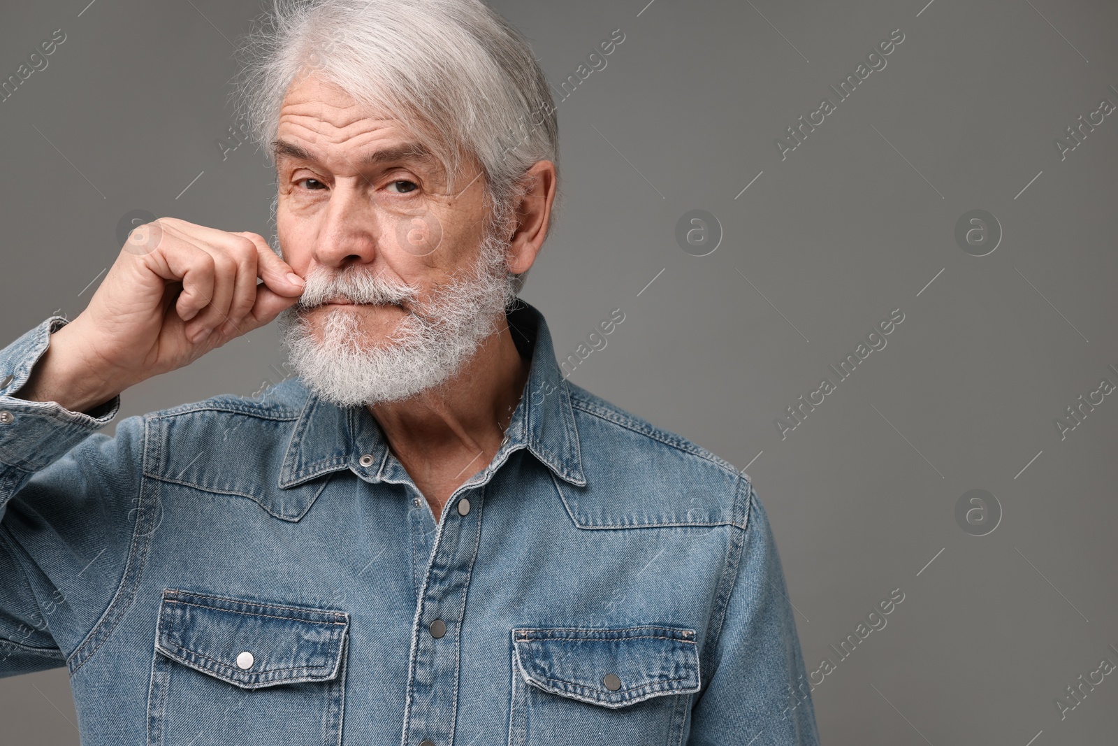 Photo of Senior man touching mustache on grey background, space for text