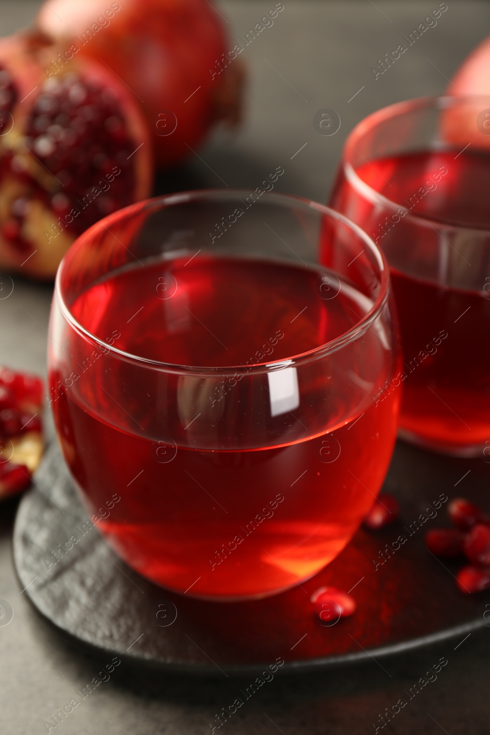 Tasty pomegranate juice in glasses on grey table, closeup Photo of Tasty pomegranate juice in glasses on grey table, closeup